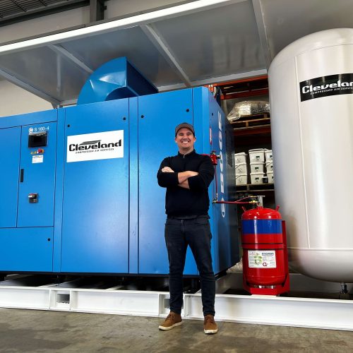Aaron O'Connor standing in from of a customised air compressor solution of a 1000 Volt Skid Packages 160Kw Compressors for underground mining use. Complete with fire suppression.