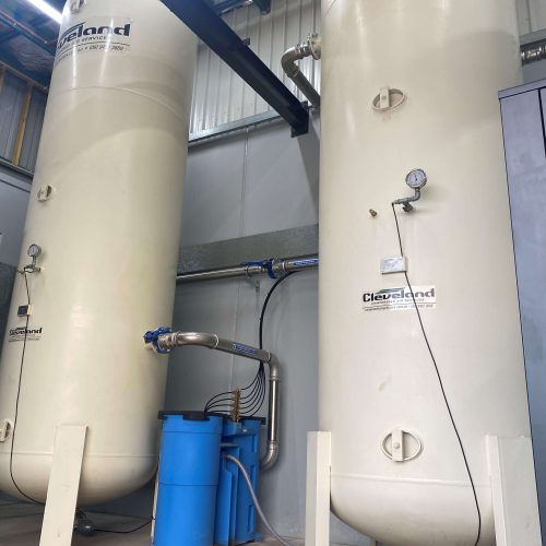 Two Cleveland Compressors air receiver tanks with integrated stainless steel piping and filtration systems installed in an industrial facility, showcasing a robust and efficient compressed air setup.